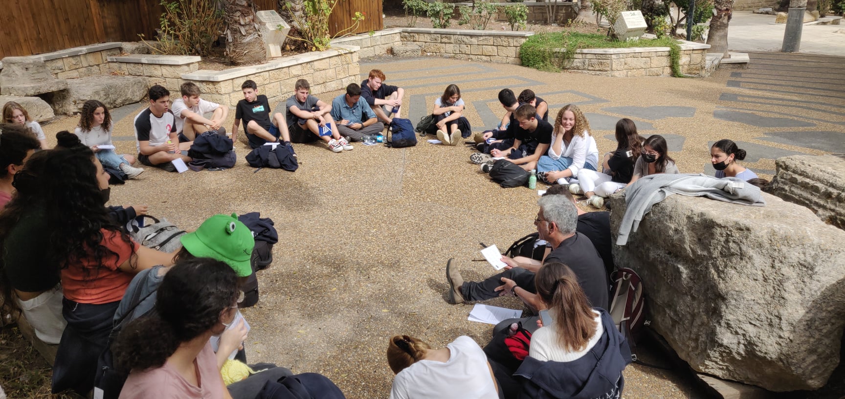 קבוצת תלמידים במעגל שיח על רצפת אבן בגן חינוכי בישראל